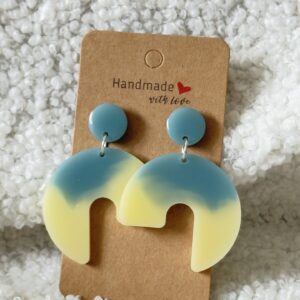 Paire de boucles d'oreilles en résine époxy en forme de 3/4 de rond surmontées d'un rond au niveau de l'attache, attachées à un carton fait main