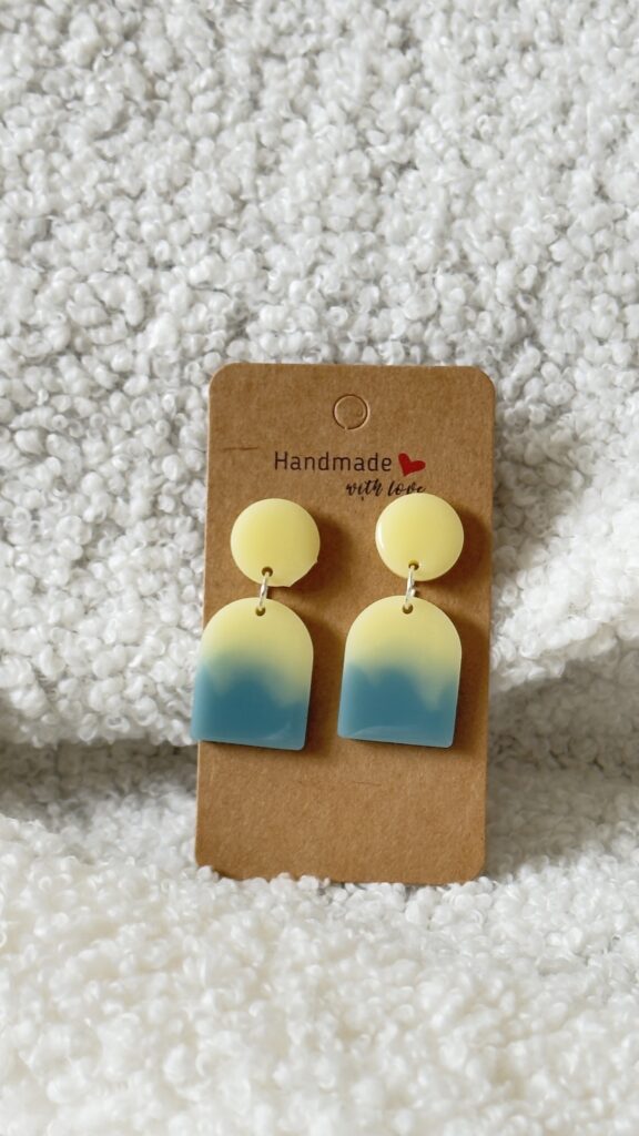 Paire de boucles d'oreilles en résine époxy en forme de "U" plein surmontées d'un rond au niveau de l'attache, attachées à un carton fait main
