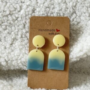Paire de boucles d'oreilles en résine époxy en forme de "U" plein surmontées d'un rond au niveau de l'attache, attachées à un carton fait main
