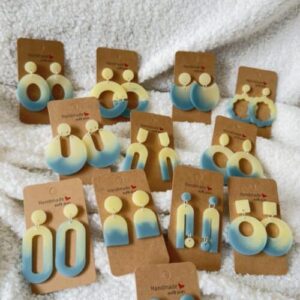Collection de boucles d'oreilles en résine époxy bicolores jaune et bleu mer en forme d'oval creux surmonté d'un rond au niveau de l'attache attachées à un carton fait main