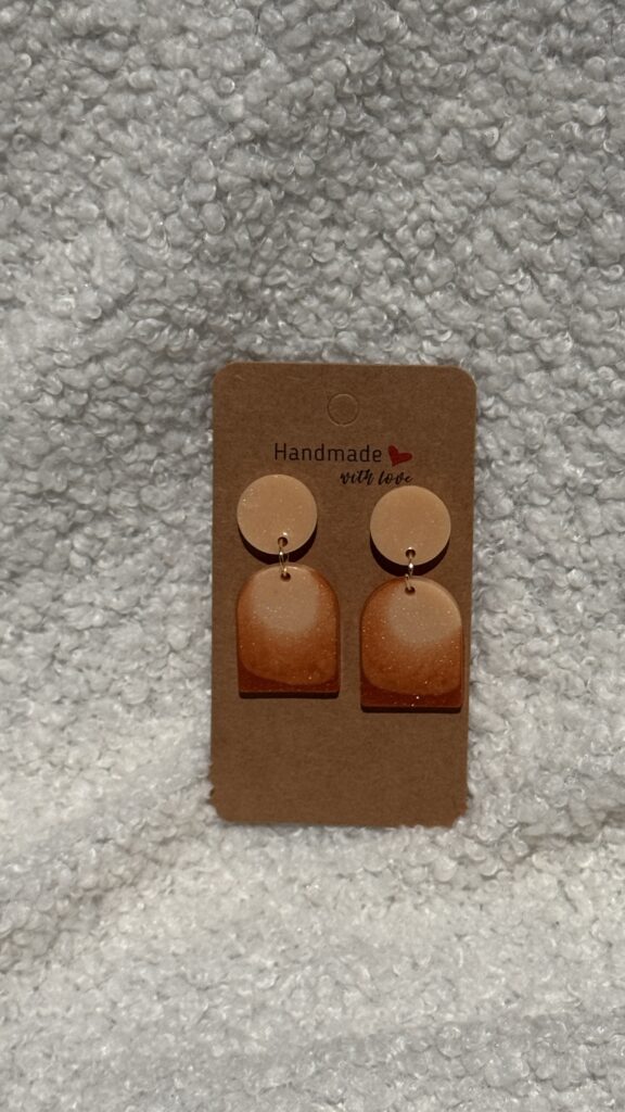 Paire de boucles d'oreilles en résine époxy en forme de "U" plein surmontées d'un rond au niveau de l'attache, attachées à un carton fait main