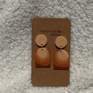 Paire de boucles d'oreilles en résine époxy en forme de "U" plein surmontées d'un rond au niveau de l'attache, attachées à un carton fait main