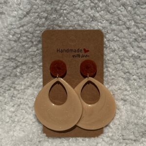Paire de boucles d'oreilles en résine époxy en forme de goutte creuse surmontées d'un rond au niveau de l'attache, attachées à un carton fait main