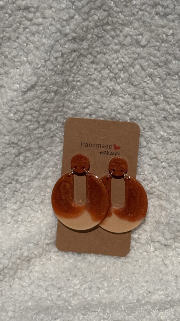 Paire de boucles d'oreilles en résine époxy en forme de Pacman inversé surmontées d'un rond au niveau de l'attache, attachées à un carton fait main