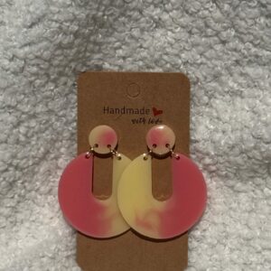 Paire de boucles d'oreilles en résine époxy en forme de Pacman inversé surmontées d'un rond au niveau de l'attache, attachées à un carton fait main