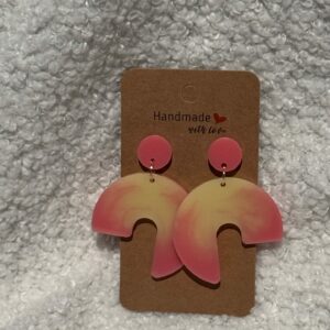 Paire de boucles d'oreilles en résine époxy en forme de 3/4 de rond surmontées d'un rond au niveau de l'attache, attachées à un carton fait main