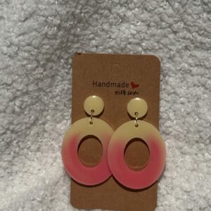 Paire de boucles d'oreilles en résine époxy en forme d'oval creux surmonté d'un rond au niveau de l'attache attachées à un carton fait main