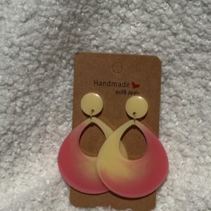 Paire de boucles d'oreilles en résine époxy en forme de goutte creuse surmontées d'un rond au niveau de l'attache, attachées à un carton fait main
