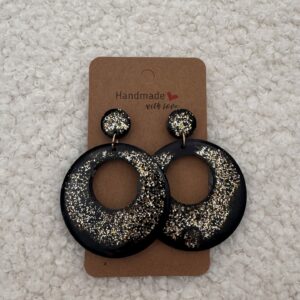 Paire de boucles d'oreilles en résine époxy en forme ronds creux surmontés d'un rond au niveau de l'attache, attachées à un carton fait main