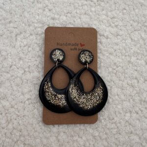 Paire de boucles d'oreilles en résine époxy en forme de goutte creuse surmontées d'un rond au niveau de l'attache, attachées à un carton fait main