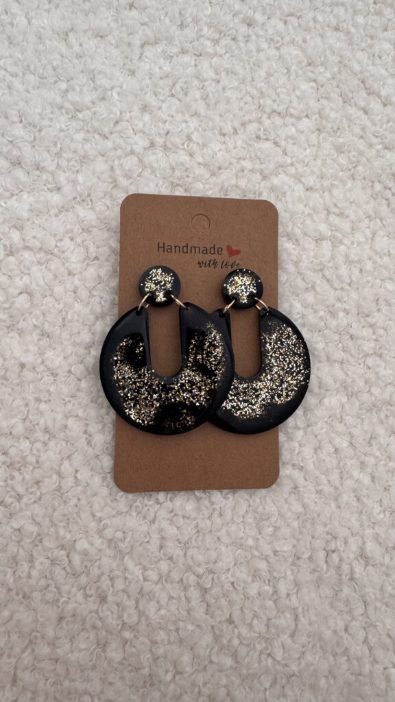 Paire de boucles d'oreilles en résine époxy en forme de Pacman inversé surmontées d'un rond au niveau de l'attache, attachées à un carton fait main