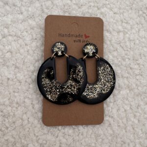 Paire de boucles d'oreilles en résine époxy en forme de Pacman inversé surmontées d'un rond au niveau de l'attache, attachées à un carton fait main